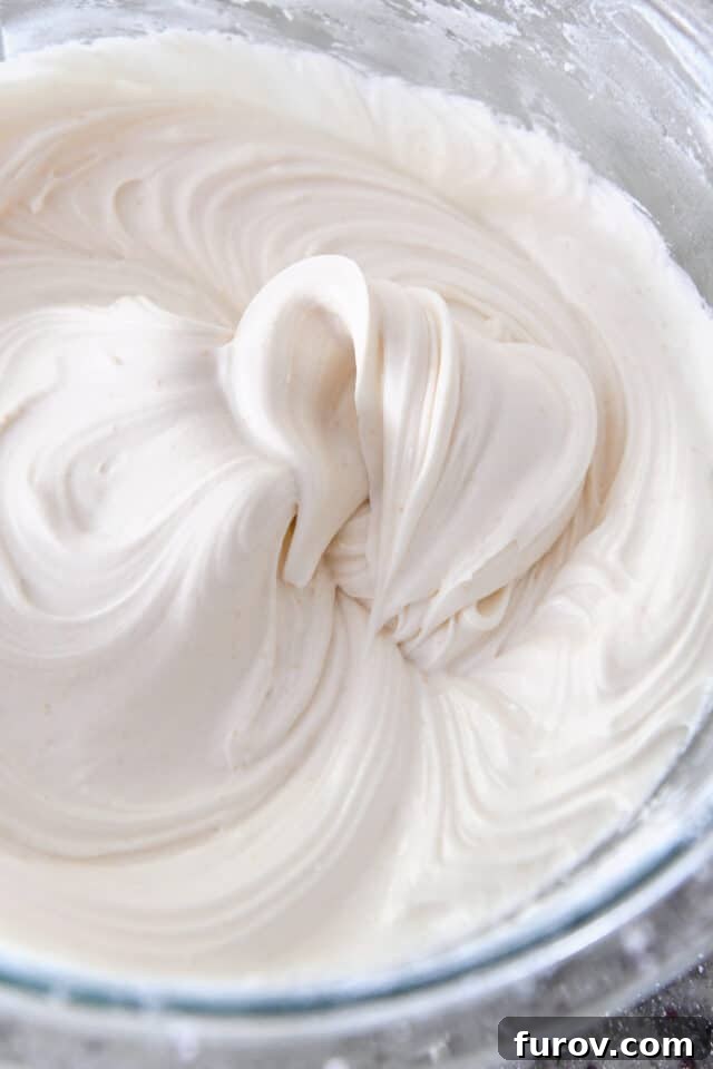 Spiced Apple Comfort Cake with Brown Butter Cream Cheese Swirl 8 Glass bowl with whipped creamy frosting.