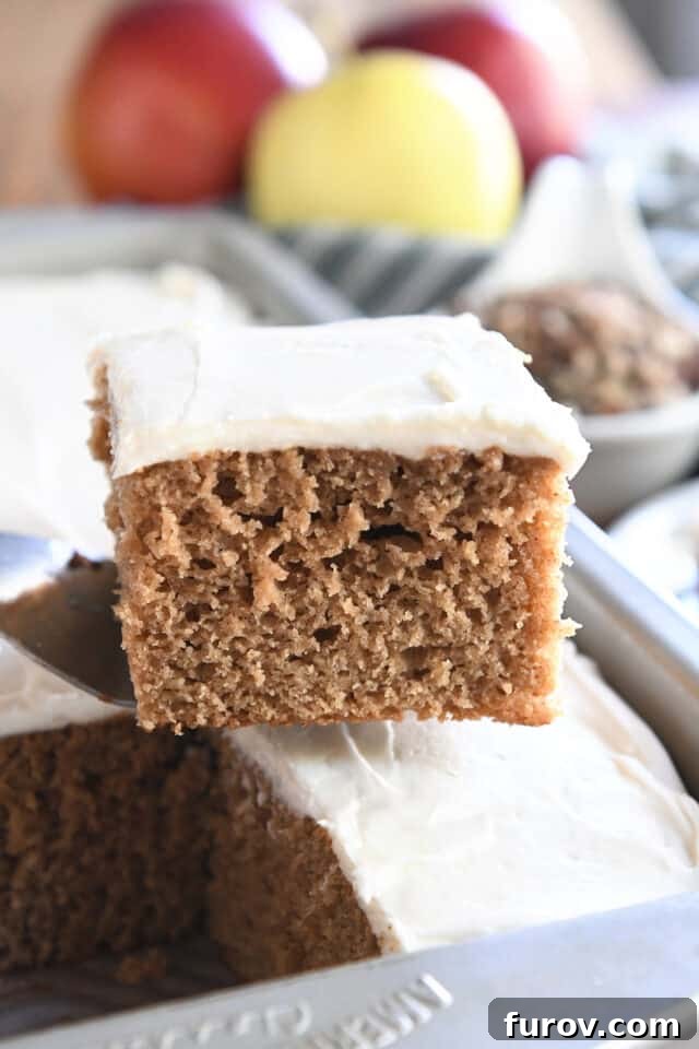 Spiced Apple Comfort Cake with Brown Butter Cream Cheese Swirl 10 Square of frosted applesauce spice cake on spatula.