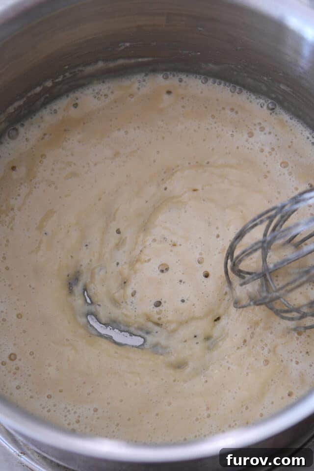 Cooking roux in saucepan with whisk.