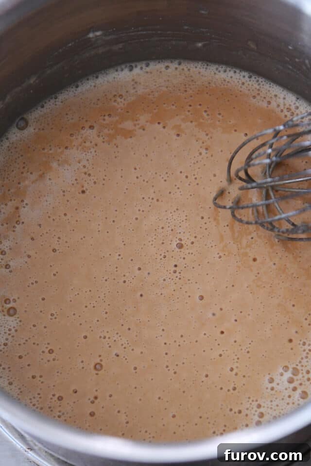Cooking roux for gravy in pan with whisk.