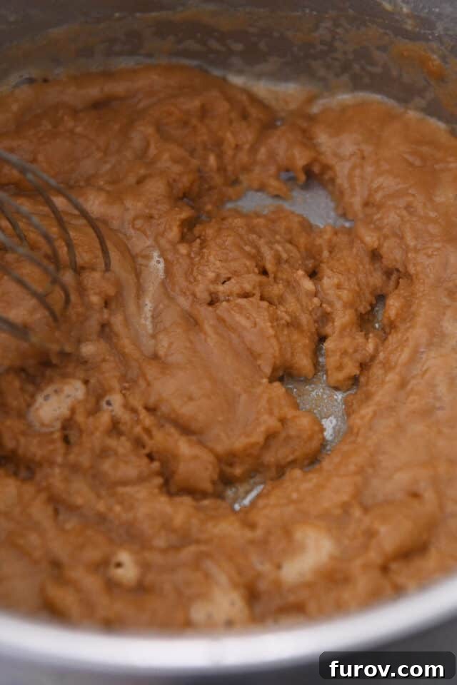 Roux with broth in saucepan.