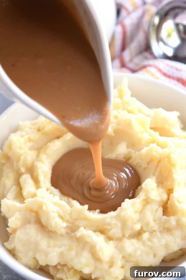 Pouring gravy from gravy boat onto mashed potatoes.