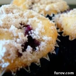 Close-up of a single blueberry crumb muffin showing its golden streusel topping and moist interior.