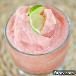 A close-up of a pink watermelon smoothie topped with a slice of lime.