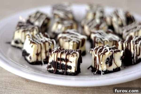 White plate with Oreo-studded cheesecake bites drizzled with white and dark chocolate, showcasing their rich texture.