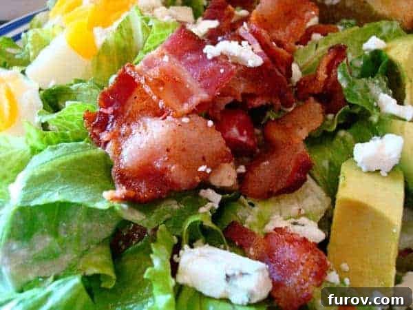 A vibrant and fresh chopped Cobb Salad featuring crispy bacon, tender chicken, sliced avocado, hard-boiled eggs, and crumbled blue cheese, arranged beautifully in a bowl.