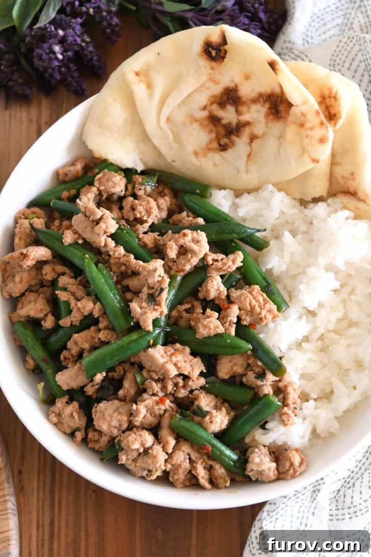 20-Minute Thai Turkey & Green Bean Dinner 7 A complete serving of Thai-style ground turkey and green beans, beautifully arranged with rice and naan bread in a pristine white bowl, showcasing a hearty and flavorful meal.
