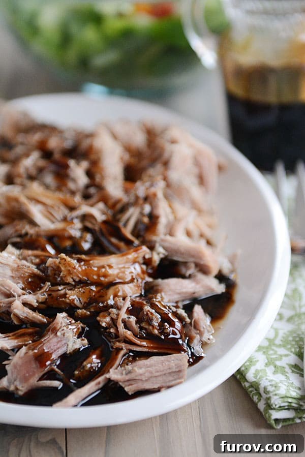 A beautifully plated dish of shredded balsamic glazed pork, showcasing the glossy texture of the glaze and the succulent meat on a white plate.