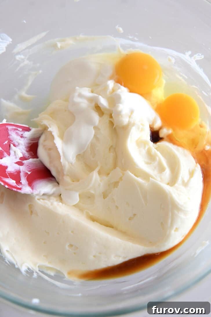 Irresistible Bite-Sized Cheesecakes 7 Glass bowl with cheesecake batter, eggs, vanilla and sour cream.