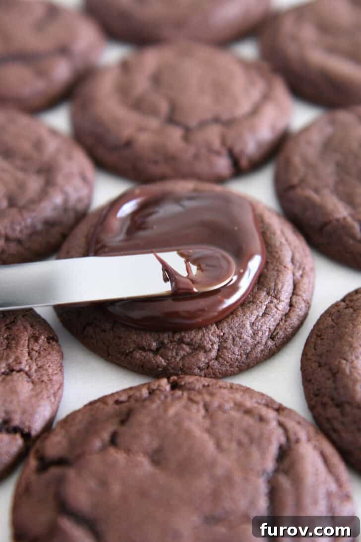 Spreading chocolate ganache on fudgy brownie cookie with offset spatula.