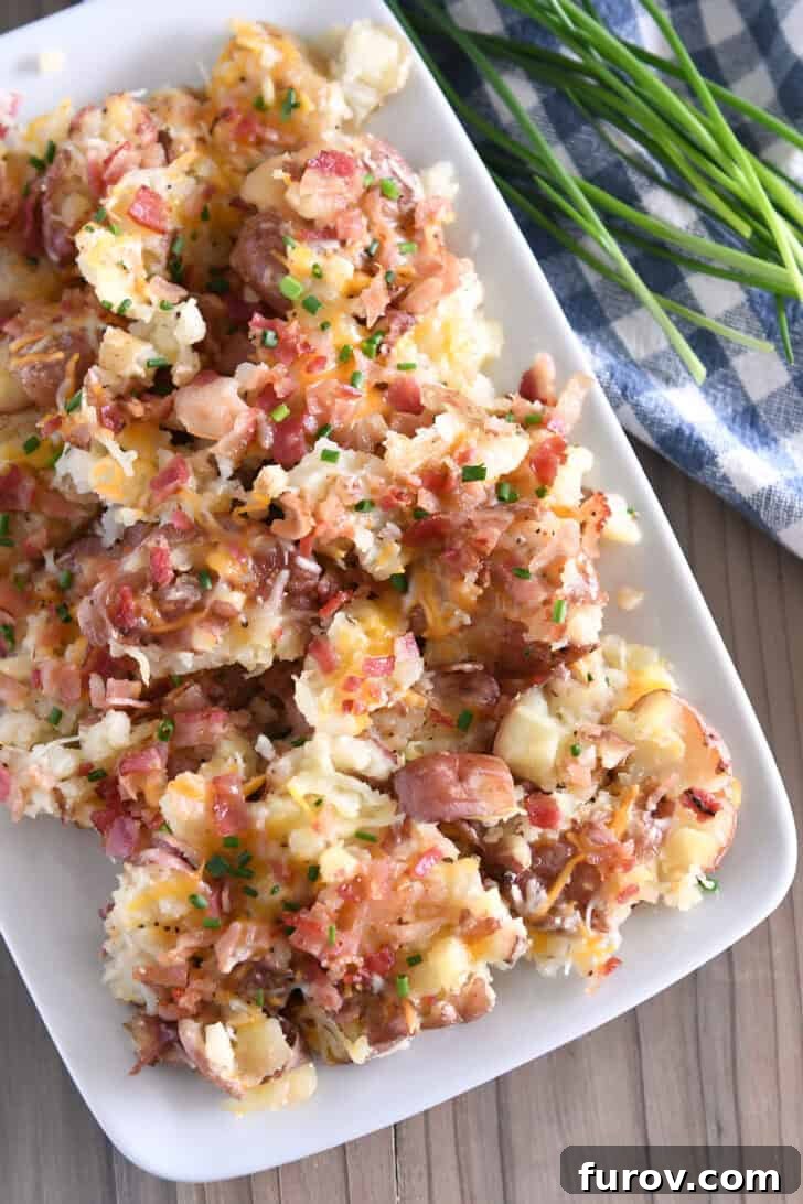 Top down view of white platter with cheesy smashed potatoes.