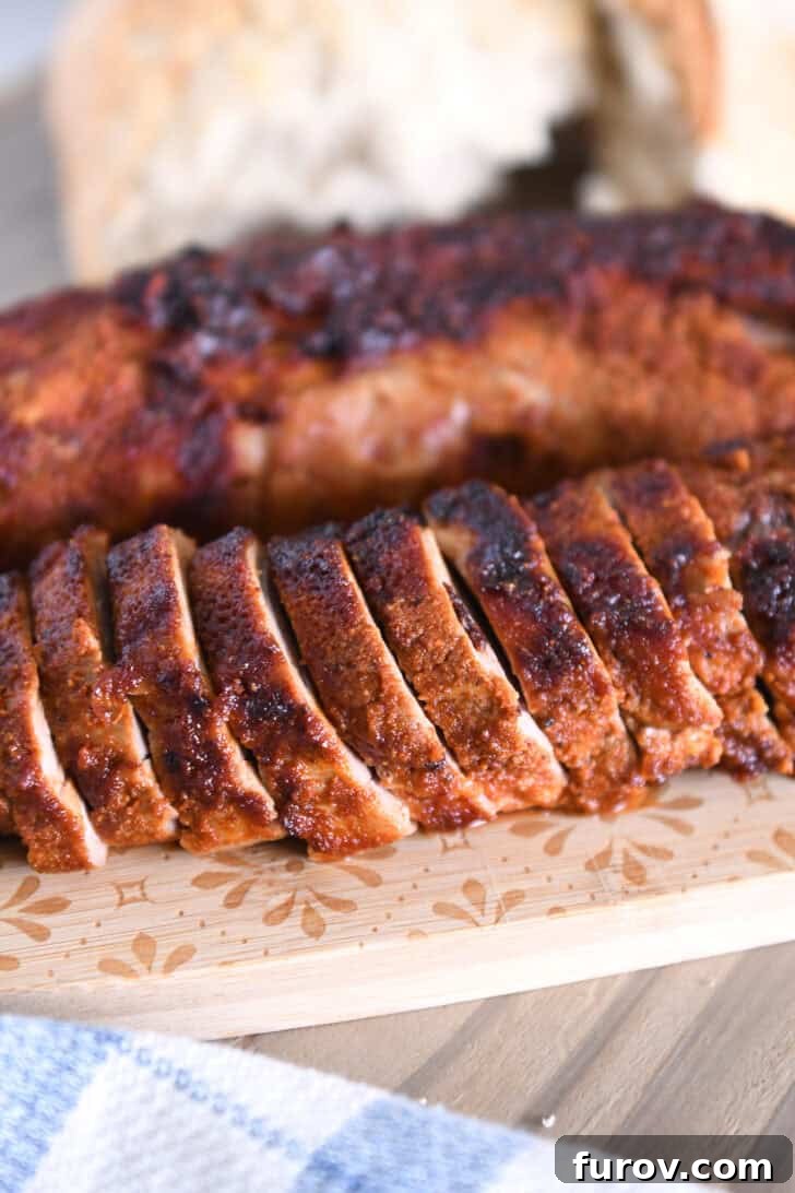 Speedy and Succulent Air Fryer Pork Tenderloin 2 Slices of air fryer pork tenderloin on wood cutting board, showcasing its juicy interior and crispy exterior.