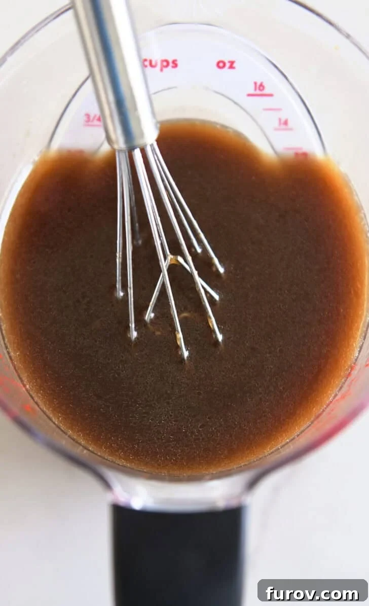 Liquid measuring cup with small whisk and Asian-style dressing.