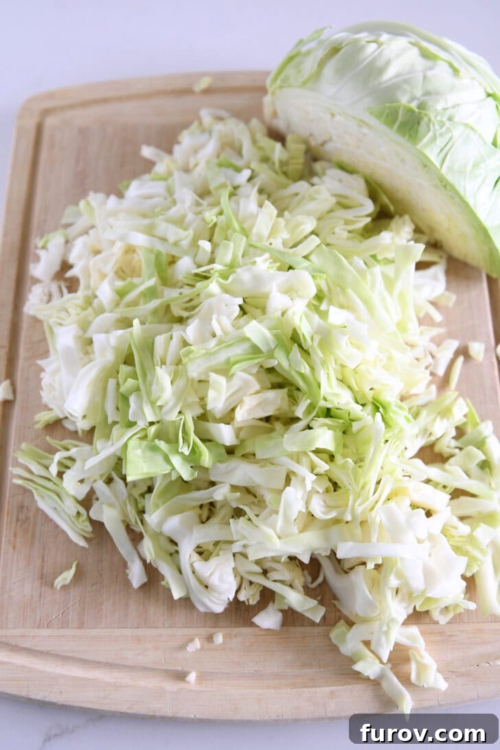 Chopped green cabbage on wood cutting board.