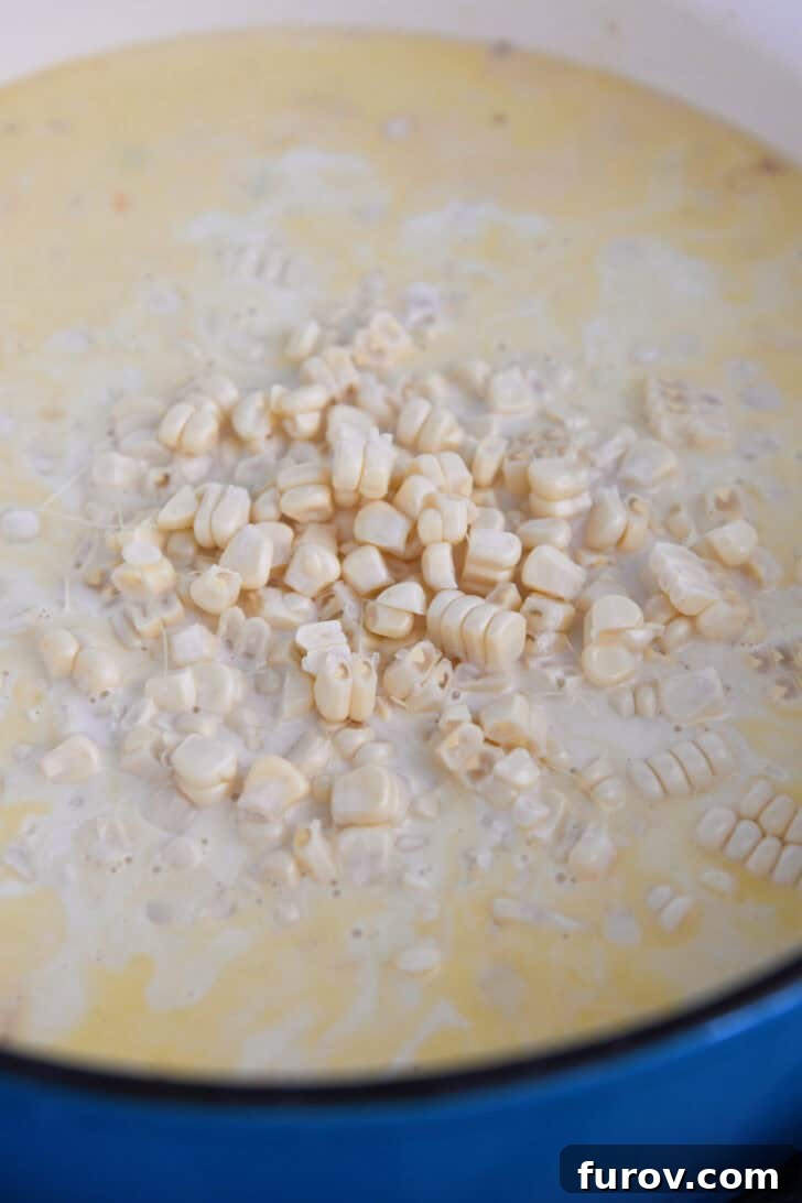 Abundant fresh corn kernels glistening in a Dutch oven pot, mixed with the creamy chowder base and other vibrant ingredients.