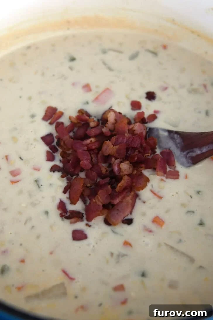 Crispy cooked bacon pieces artfully sprinkled into a thick and creamy corn chowder, adding a smoky, savory finish.
