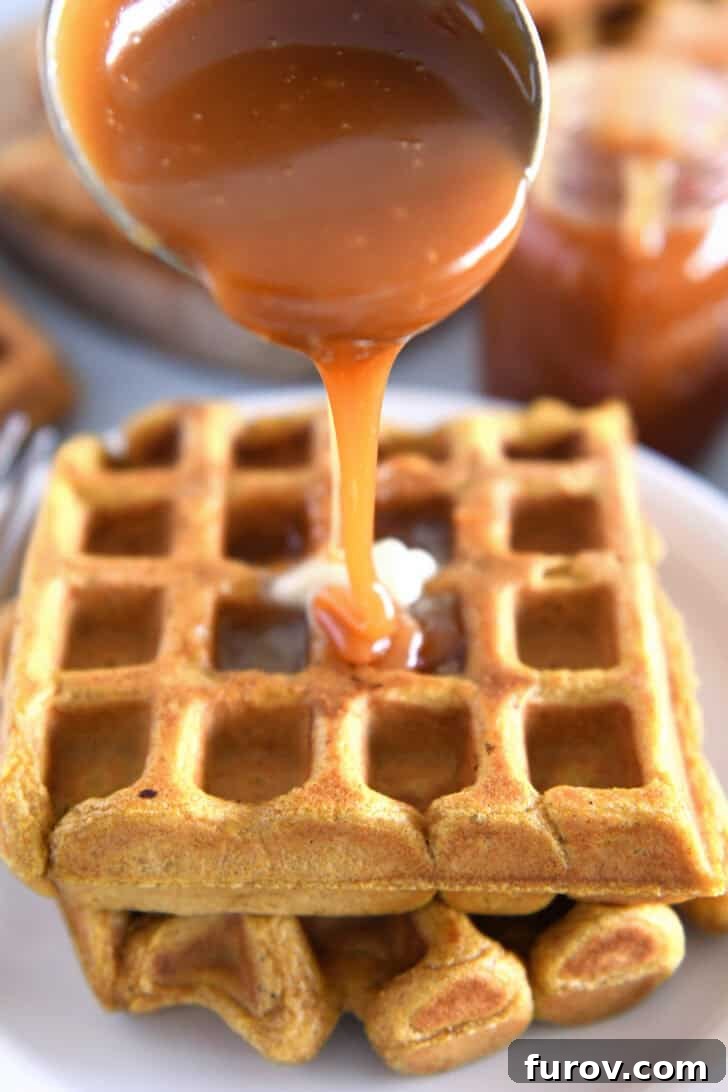 Small ladle elegantly drizzling thick, golden buttermilk caramel syrup over a stack of fluffy pumpkin waffles on a pristine white plate.