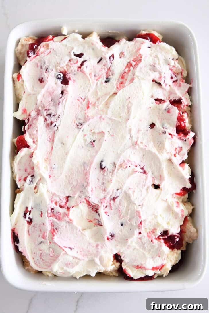 The finished Cranberry Orange Angel Food Cake Dessert in a white baking dish, chilling in the refrigerator.