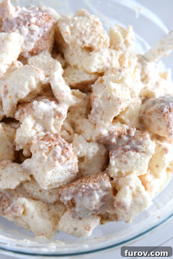 Glass bowl with angel food cake cubes generously tossed with the creamy mixture.