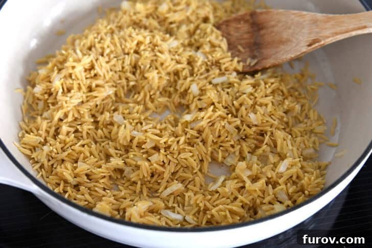 White pan with toasted orzo and onions.
