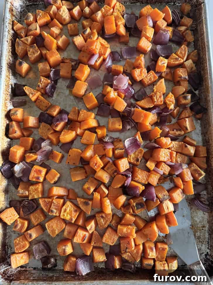 Sheet pan with roasted sweet potatoes and red onions.
