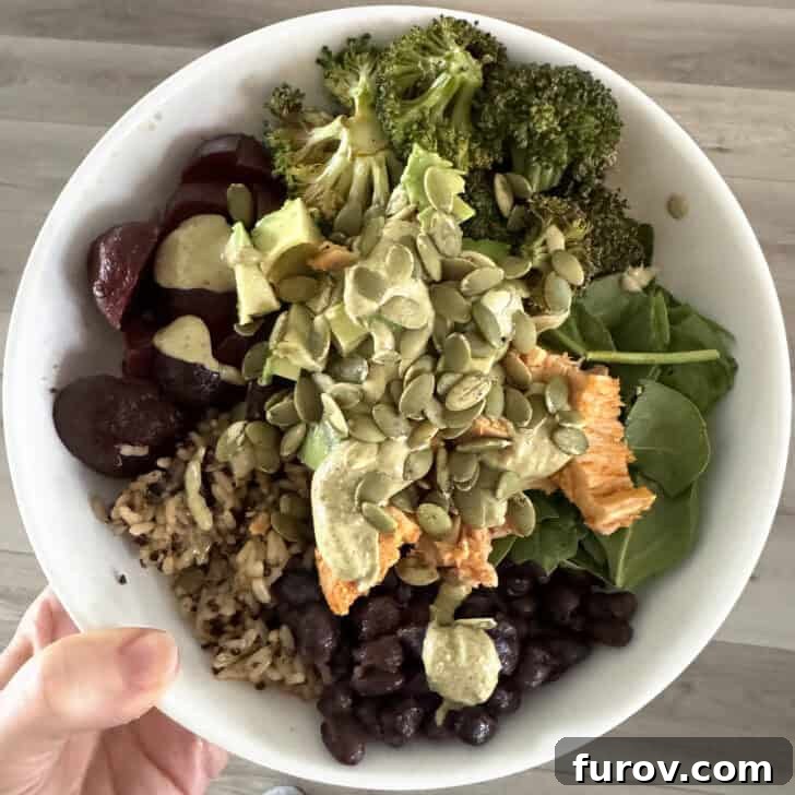 White bowl with beets, pumpkin seeds, tuna, spinach, broccoli, black beans and brown rice.