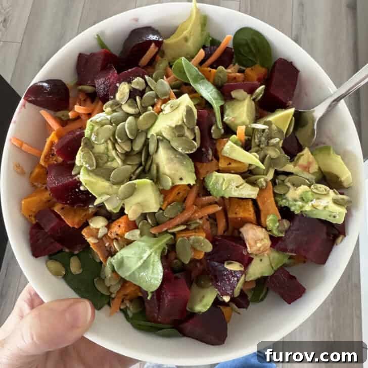White bowl with beets, sweet potatoes, avocados, pumpkin seeds, spinach and tuna.