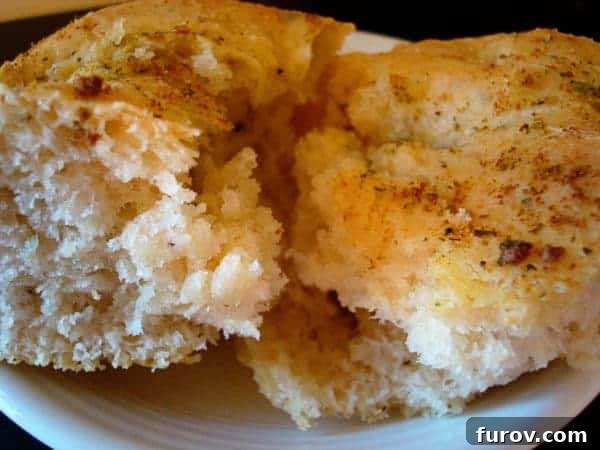 Two golden-brown pieces of herb-coated Blitz Bread, featuring a perfectly crusted exterior and tender interior, presented invitingly on a white plate, ready to be enjoyed.