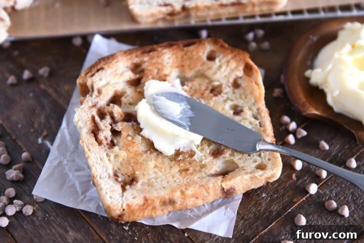 A close-up shot of a toasted slice of Cinnamon Burst Bread with a generous pat of butter melting into its warm, cinnamony surface, highlighting its soft texture.