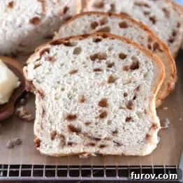 Slice of cinnamon burst bread on brown parchment paper with butter on wooden dish to the side.