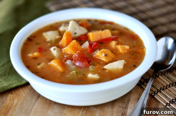 A hearty white bowl of spicy or not chicken and sweet potato soup, garnished with fresh herbs, ready to be enjoyed as a warming winter meal.