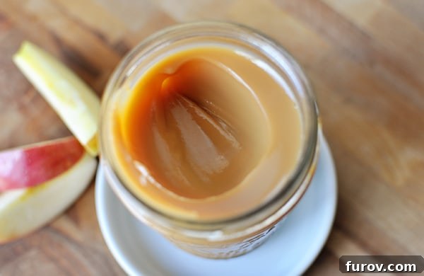 Whip Up Your Own Dulce de Leche 4 A beautiful top-down shot of a glass mason jar filled with luscious, golden dulce de leche, with a single scoop already taken out, highlighting its creamy perfection.