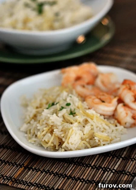 White plate with cooked rice pilaf next to cooked shrimp.