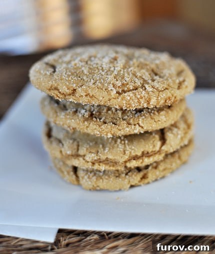 Chewy Brown Sugar Crinkle Cookies 2 A stack of four sugar-coated brown sugar cookies on a piece of parchment, showcasing their beautiful crackled tops and chewy texture.