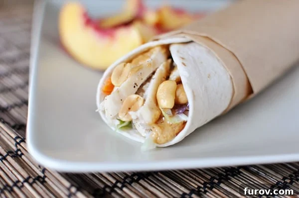 White tortilla wrap filled with Asian chicken and peanut sauce, with fresh peach slices in the background.