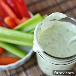 Homemade Ranch Dressing in a mason jar with fresh vegetables behind it.