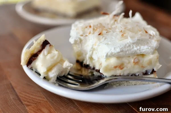 Dreamy Chocolate Coconut Cream Bars 2 A layered coconut cream pie bar with a bite taken out on a white plate, revealing the golden crust, dark chocolate, and white coconut cream.