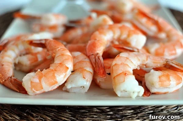 A white platter showcasing perfectly cooked, vibrant pink shrimp, ready to be enjoyed.
