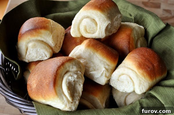 Signature Lion House Dinner Rolls 3 Close-up of golden brown Lion House dinner rolls artfully arranged on a green napkin inside a black woven basket, highlighting their inviting texture.