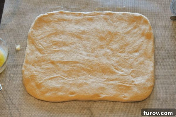 Signature Lion House Dinner Rolls 5 Smooth bread dough expertly rolled into a large, even rectangle on a clean surface, ready for the next shaping step.