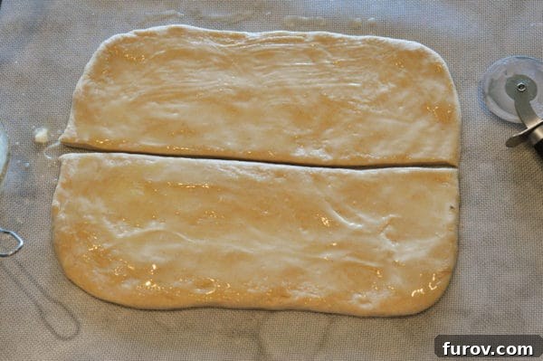 Signature Lion House Dinner Rolls 6 Bread dough, brushed with melted butter, has been cleanly sliced lengthwise into two long, even rectangles.