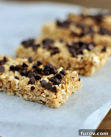 Homemade chewy granola bars with chocolate chips, neatly lined up on parchment paper.