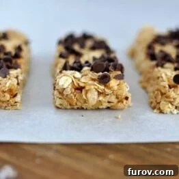 Close-up of golden oat granola bars topped with a sprinkle of mini chocolate chips.