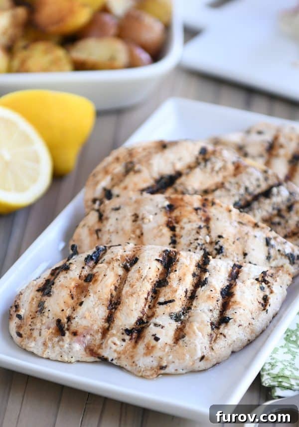 A serving platter filled with beautifully charred and juicy lemon garlic grilled chicken breasts.