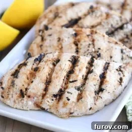 A vibrant close-up of a perfectly cooked lemon garlic grilled chicken breast.