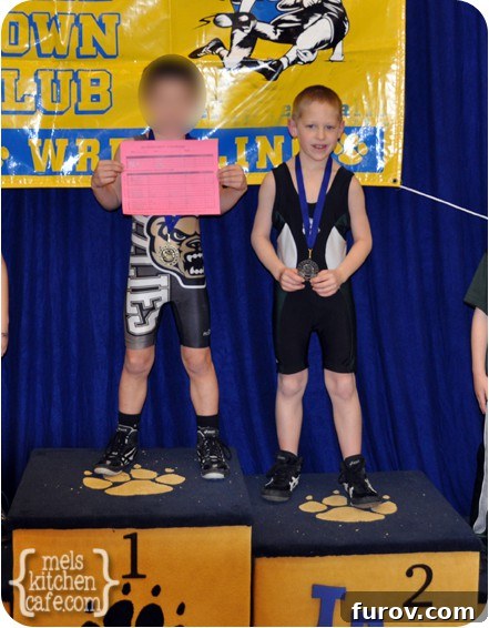 A young wrestler standing confidently on the podium, symbolizing strength, toughness, and achievement in the demanding sport of wrestling.