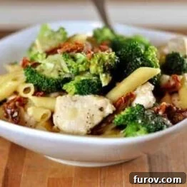 Close-up of Skillet Chicken Pasta with Broccoli and Sun-Dried Tomatoes in a rustic bowl.