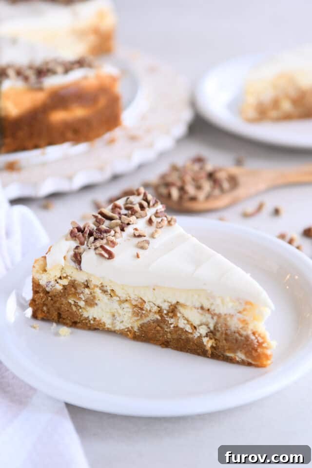 A beautifully sliced piece of Carrot Cake Cheesecake, revealing its distinct layers of carrot cake and creamy cheesecake, topped with smooth cream cheese frosting, resting on a pristine white plate.