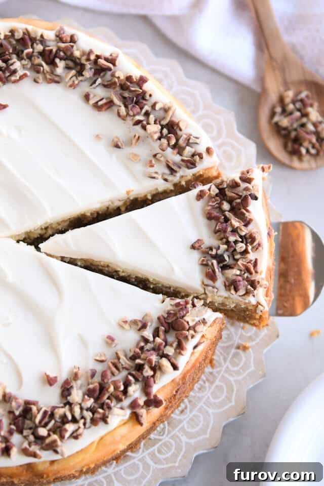 A perfectly triangular slice of Carrot Cake Cheesecake, showcasing its beautiful layers of cake and cream, perched elegantly on a cake server, ready to be enjoyed.