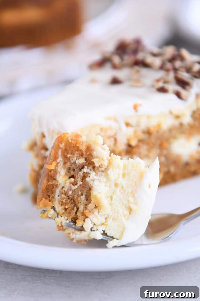 A fork holding a perfect bite of Carrot Cake Cheesecake, showing the moist cake, creamy filling, and fluffy frosting, ready to be savored.